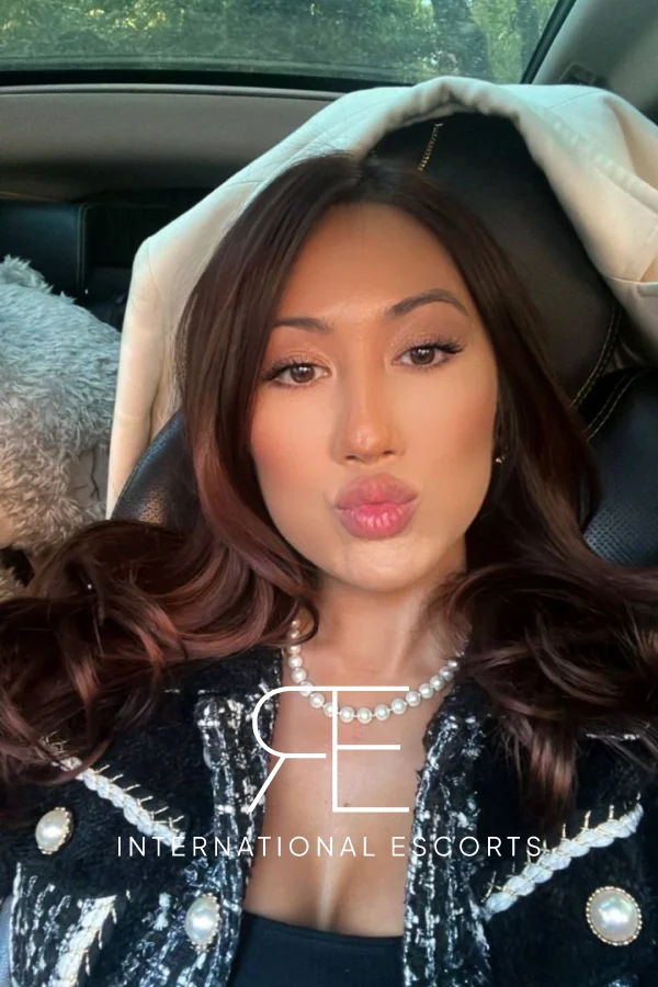 High class Asian London escort sitting in a car taking a selfie