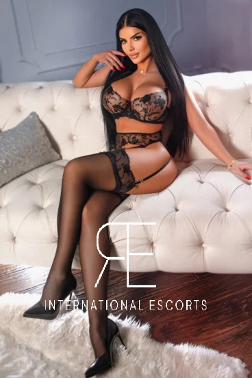 London escort sitting on a sofa wearing sexy underwear 