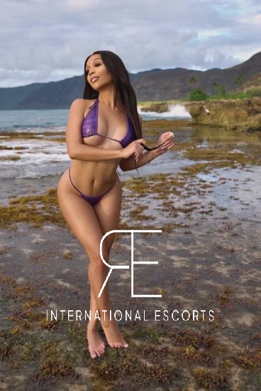 Savannah wearing a purple bikini standing by the ocean 