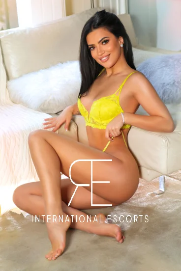 Sitting on the floor wearing yellow lingerie is this very pretty and elegant female brunette escort 