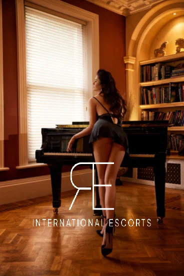 London escort Rosie is bent over a piano 