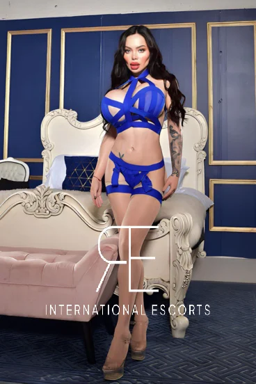A full length photo of a busty porn star named Nicole Loveee who is wearing blue lingerie 
