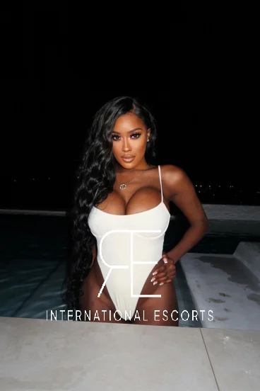 Beautiful curvy escort Halle is pictured wearing a white swim suit 