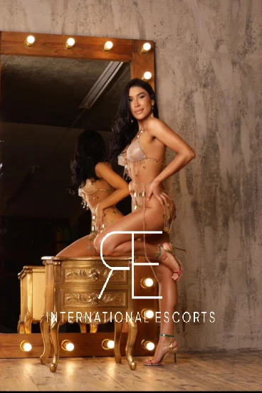 Kneeling on a cupboard and looking good in sexy gold lingerie is Brazilian escort Marley