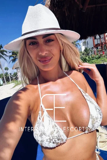 A sexy blonde lady took this selfie sitting around a swimming pool 
