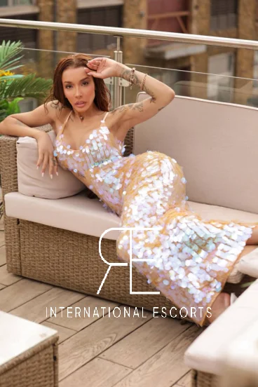 Beautiful lady laying across a sofa wearing a sexy dress 