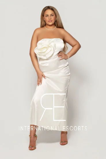 Curvy blonde escort wearing a white dress 