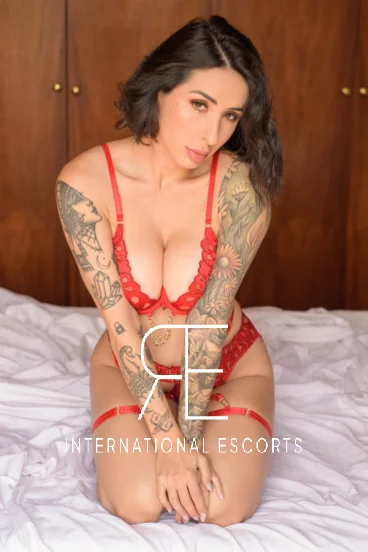 Tattooed escort wearing red lingerie 