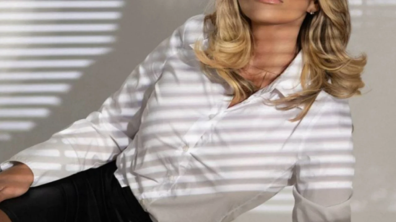 A sexy blonde lady wearing glasses getting ready to be bent over a desk 