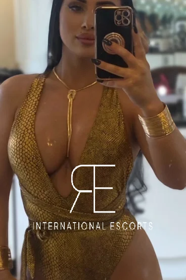 Brunette in gold swimsuit taking phone mirror pic