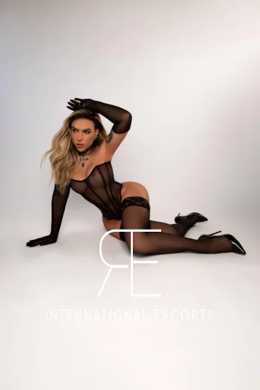 Lainey striking a sultry pose in chic black lingerie and heel