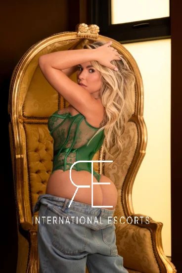 Lainey in lace corset and denim, sultry on golden chair