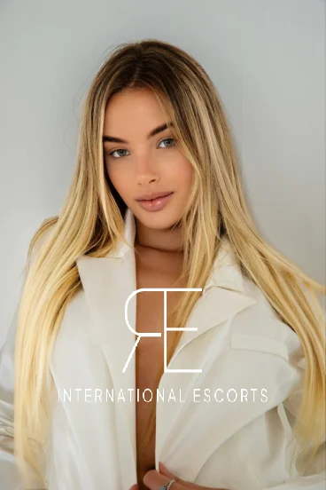Tall slim blonde escort Melissa in sporty jacket, ready for global adventures