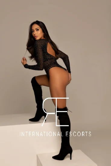 Clemmie reclining in black mesh bodysuit, high-class international escort