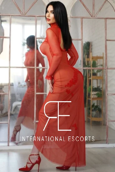 Cosmopolitan Russian Rosaline, poised in red lace gown and heels