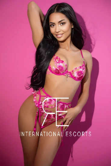 Radiant brunette in pink lingerie, floral detailing catching the light.