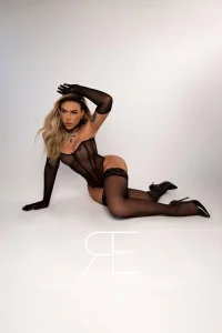 Lainey striking a sultry pose in chic black lingerie and heel